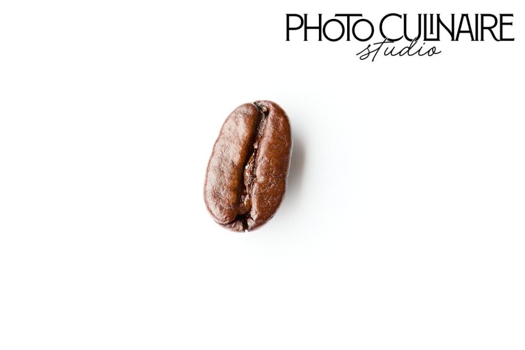 single coffee bean macro shot on plain white background negative space in food photography 