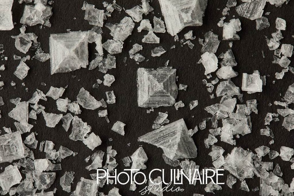 Maldon sea salt flakes on black background with incorrect white balance in food photography 